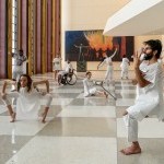 Physically diverse living human sculptures dressed in white. 