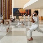 Physically diverse living human sculptures dressed in white. 