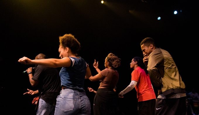 Five people of color on stage dancing in a celebratory fashion