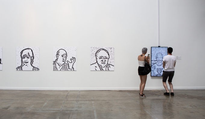 A collection of three photos in black and white with one of them on a digital screen with two people looking at them.