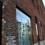 Image shows the Eyebeam office brick building, with our logo "E" neon sign in the window