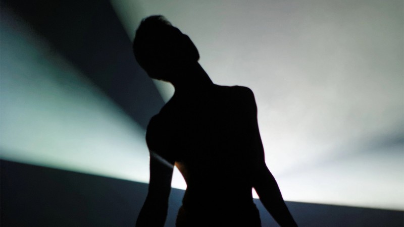 Silhouetted figure in front of a white backlight