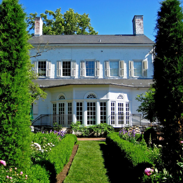 The back of Morven's large white house and garden on a sunny day.
