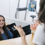 Front Desk staff in a bright office space smiling and speaking with a client