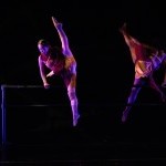 An Asian woman jumps over a ballet barre with a 180 split