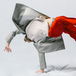 Dancer in red pants and blazer doing a flip.