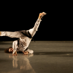 Dancer in white outfit posing in a shoulder stand position