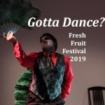 A dancer in colorful cabaret pose with giant feather fan.