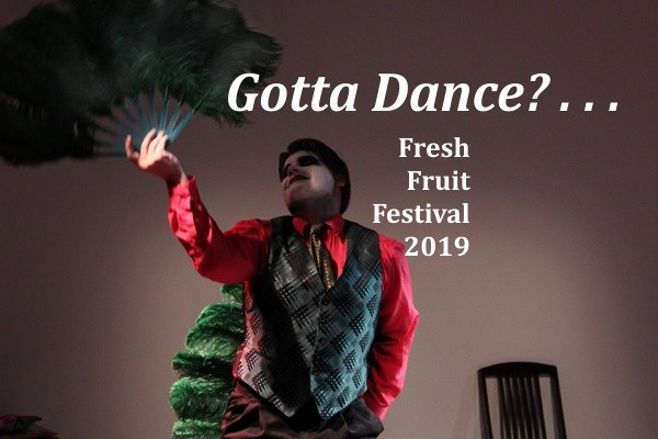 A dancer in colorful cabaret pose with giant feather fan.