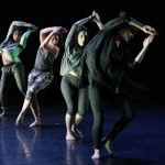 Four dancers on stage with their hands above their heads