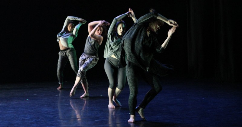 Four dancers on stage with their hands above their heads