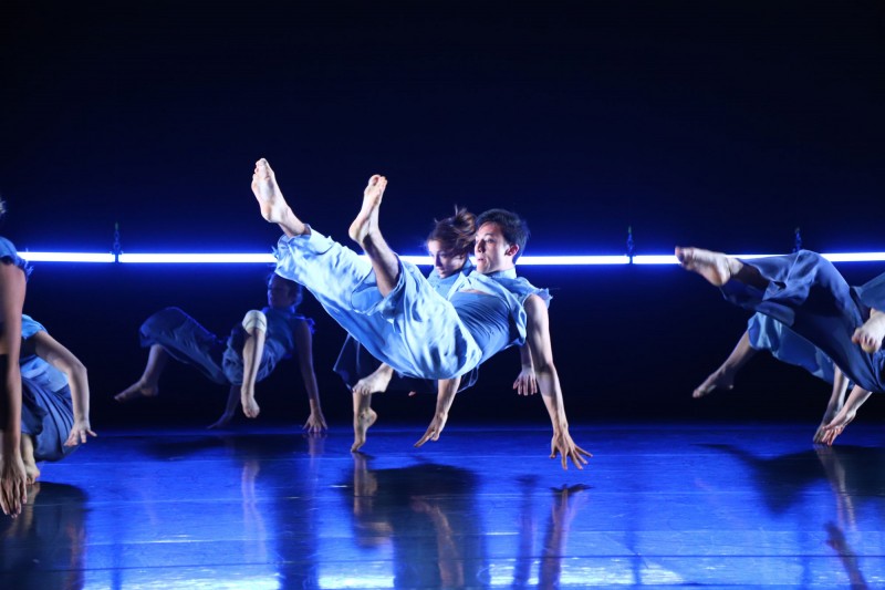Dancer doing a breakdancing move on a blue-lit stage