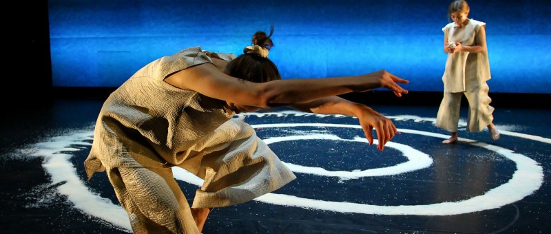 A dancer on stage in front a blue backdrop