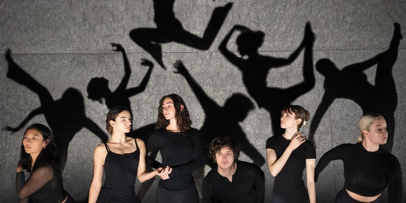 Dancers standing in front of a wall displaying their shadows