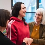 A student in red smiling while receiving hands-on from a trained Alexander Technique teacher