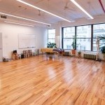 sunny studio with hardwood floors, window, massage table, stools