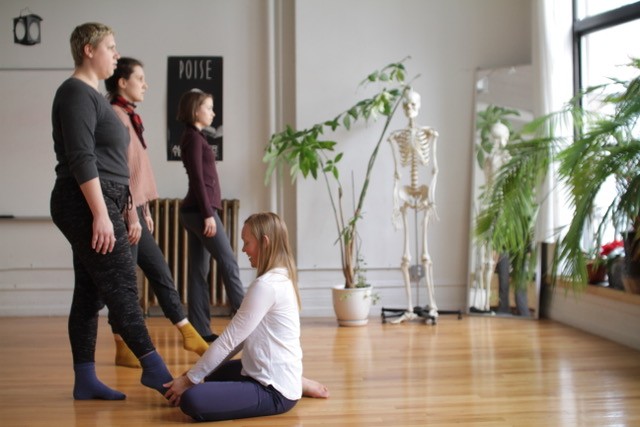 A teacher provides hands on work to a student's foot in a class at the Balance Arts Center