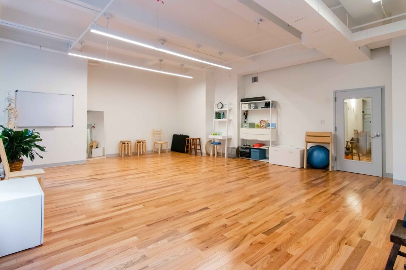sunny studio with hardwood floor and movement equipment