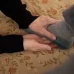 A teacher gently holding a students foot, offering direction for release with the Alexander Technique. 