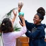 Two students hold balls in the air and are smiling