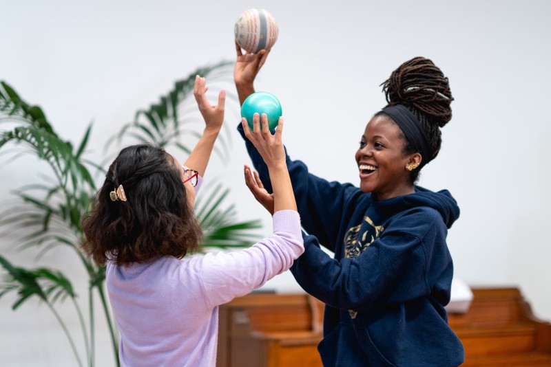 Two students hold balls in the air and are smiling
