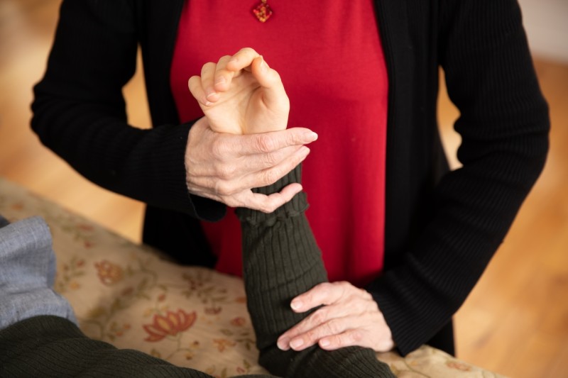 AT teacher holds wrist of student on a table, helping them find release