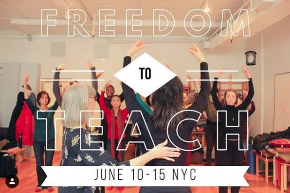 A class of dancers with their arms in the air being lead by a teacher who is receiving hands on from an Alexander teacher.