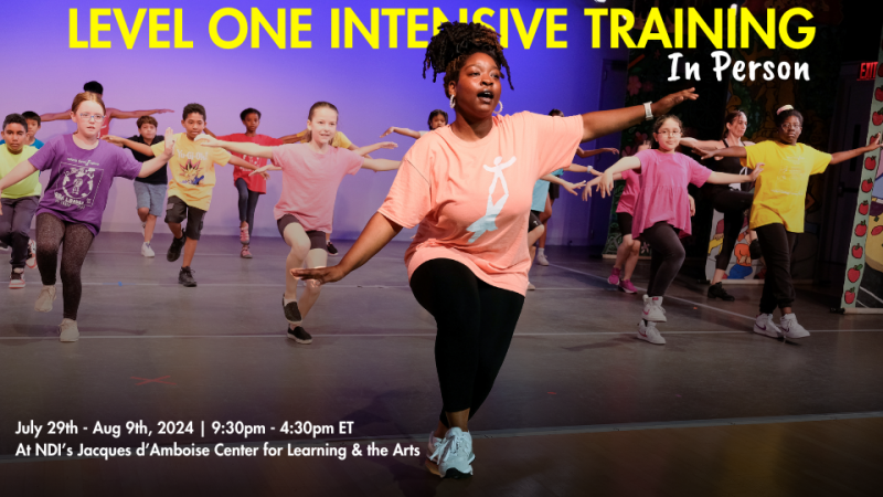 Female teacher is balancing on one leg in front of a group of young dancers that are copying the teacher's movements