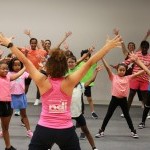 A teacher and students raise their arms above their heads.