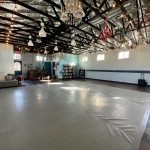 Picture of large dance studio space with gray marley floor and funky chandeliers