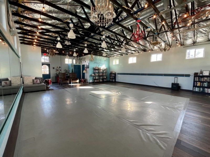 Picture of large dance studio space with gray marley floor and funky chandeliers