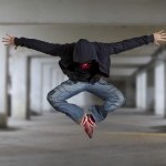 Male dancer in jeans jumping in parking lot