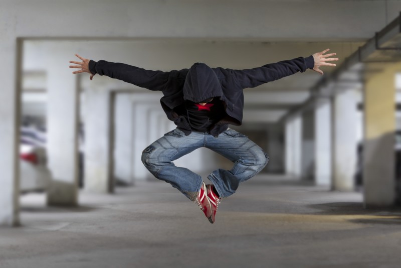 Male dancer in jeans jumping in parking lot