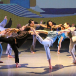 Group photo of Alison Cook-Beatty's dance, "Whale." Circular formation of dancers interlocking arms and balancing in a stag.