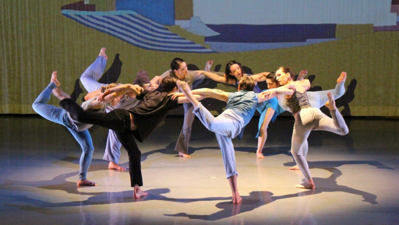 Group photo of Alison Cook-Beatty's dance, "Whale." Circular formation of dancers interlocking arms and balancing in a stag.