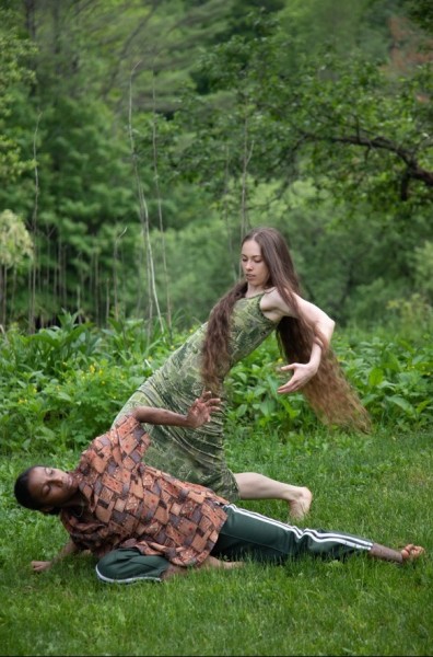 two dancers arch and create negative space in a field of green
