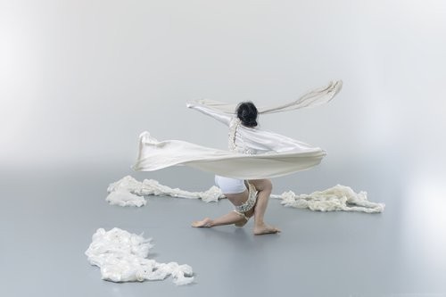 dancer swirling at mid-level with pieces of white fabric