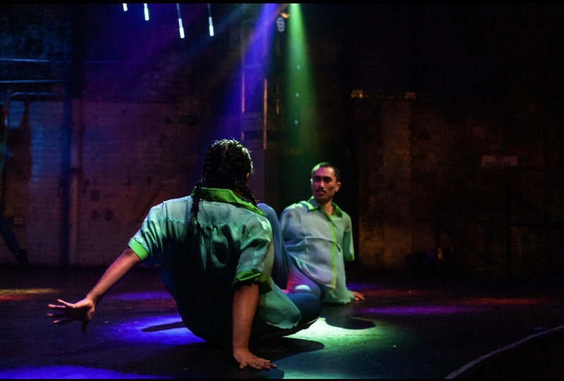 2 dancers sit and look at each other