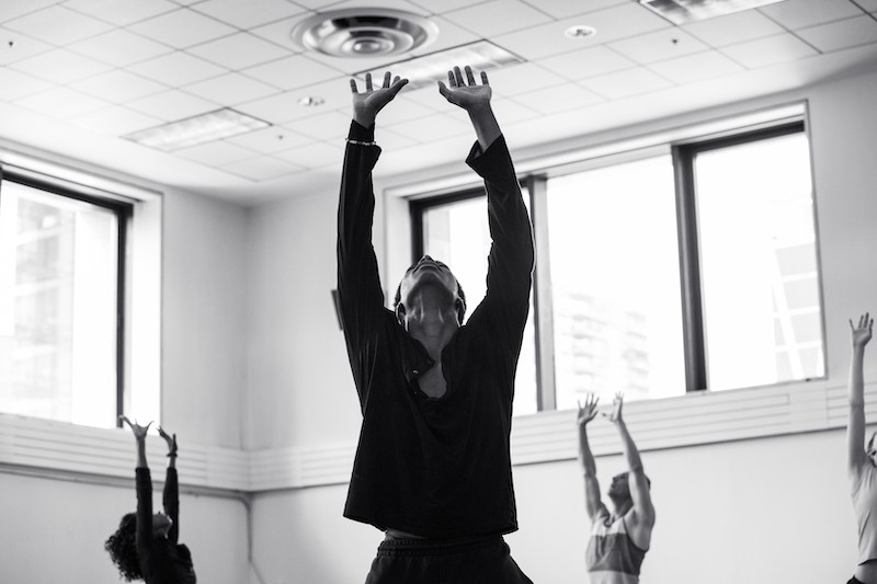 Three sufferers reaching towards the sky in a rehearsal studio. 