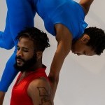Male dancer wearing red, holding female dancer (wearing blue) above his head.