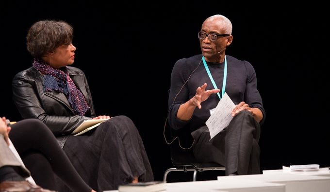 Carrie Mae Weems sits in a chair across from Bill T. Jones as they discuss James Baldwin with Jamaica Kincaid