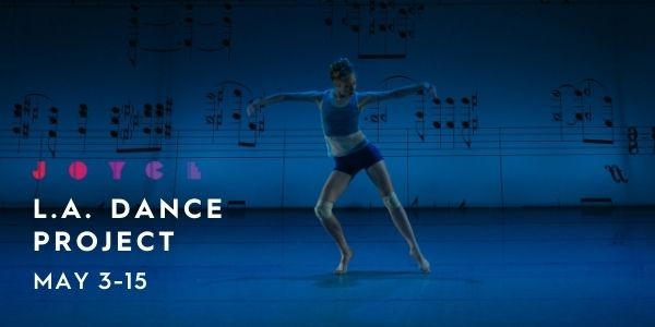 A dancer poses in front of a blue projection 