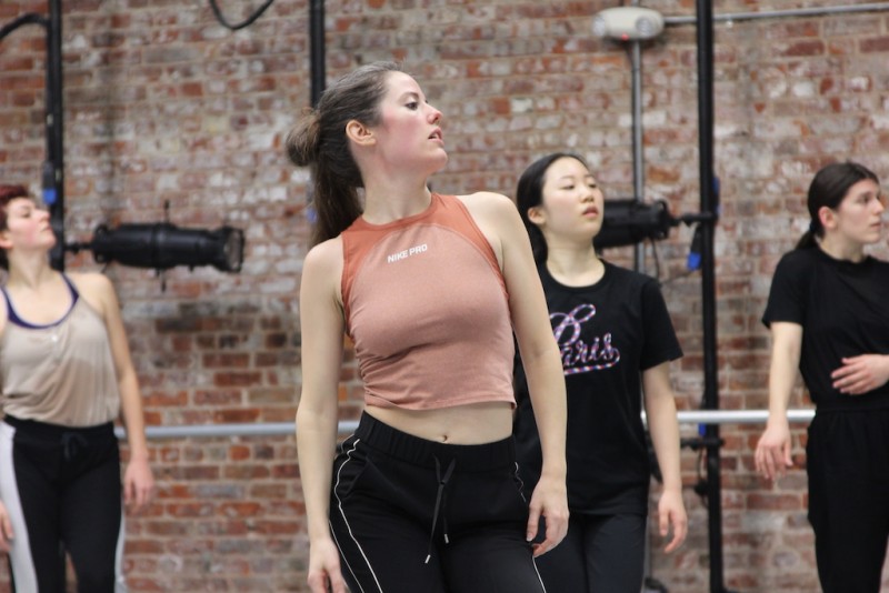 Woman standing and sitting on right hip while looking profile to the left. 