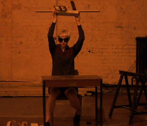 Woman sitting at a table and lifting objects overhead. 
