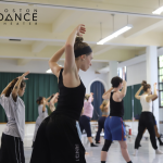 2024 SIP participant Leslie stands facing right with her arms up behind her head