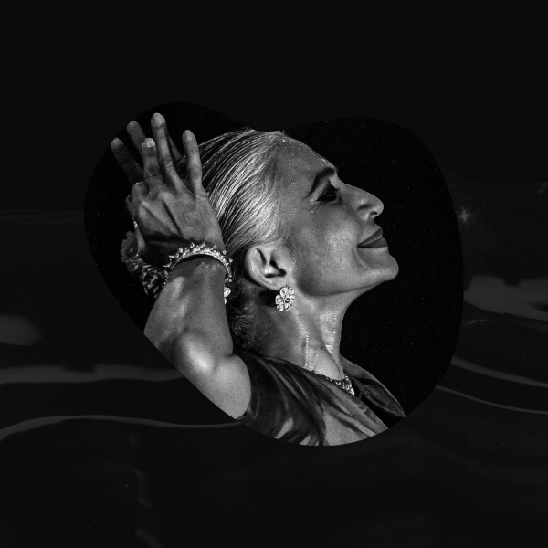 Black and white photograph of Bijayini Satpathy. She is looking up with a smile and her hands on her head.