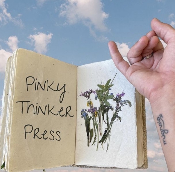 a pinky finger gestures towards a book 