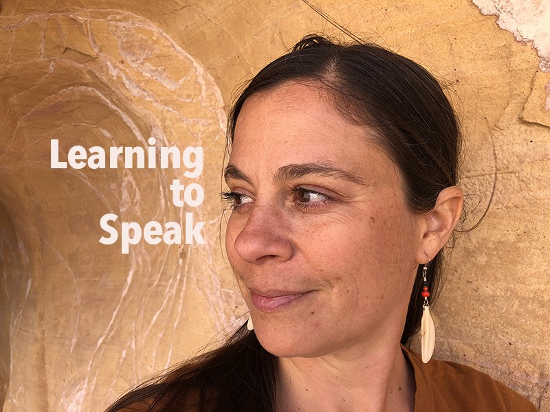 brooke smiley- a woman with light brown skin and dark brown hair, a side parted low pony tail, gazes over her right shoulder.
