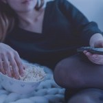 Person Watching TV and Eating Popcorn