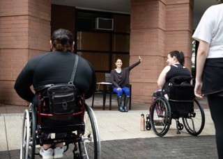 Sofia is seen teaching an outdoor seated dance class to wheelchair users. 